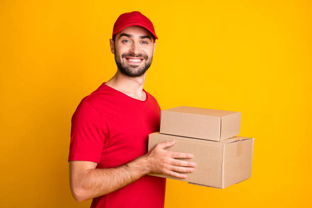 istock Profile side view portrait of nice content cheerful guy mailman holding in hands parcels fast bring isolated over bright yellow color background 1306515160