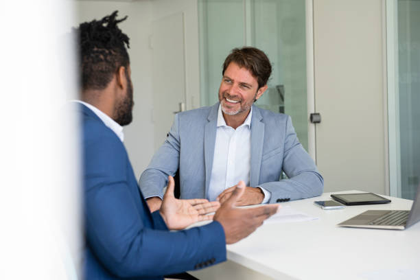 istock Smiling businessmen talking with each other during meeting in office 1306515219