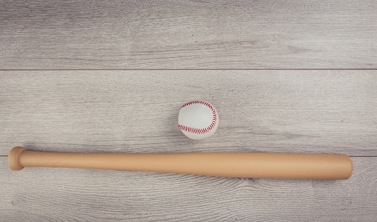 Baseball ball and baseball bat on wooden table background, flat lay concept. No people.