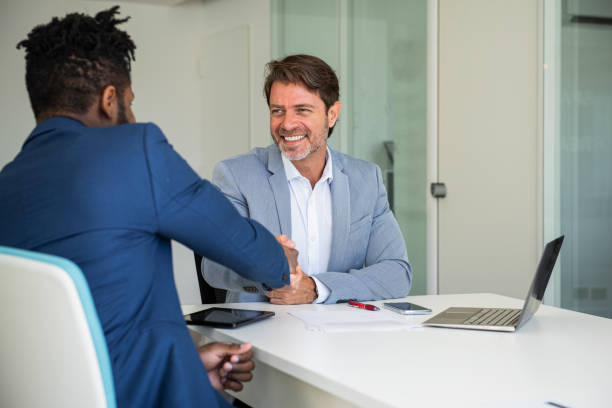 istock Smiling businessmen shaking hands with each other in office 1306515284