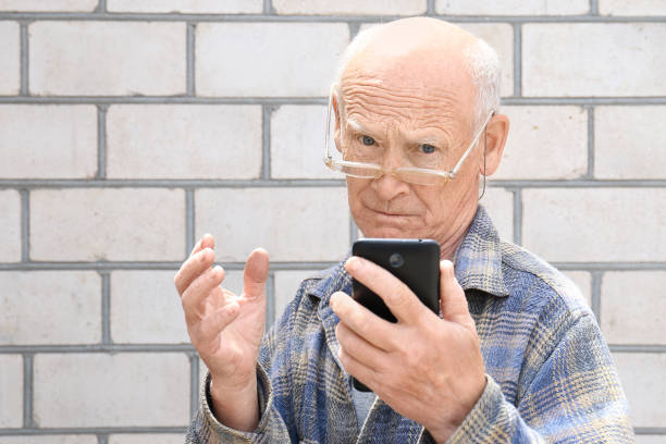 istock Elderly man with mobile phone on light background 1306515368