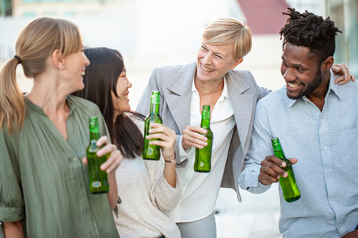 Smiling work colleagues enjoying drinks on balcony in office building