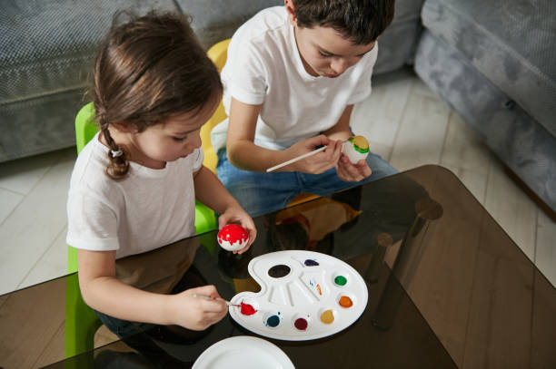 istock High angle view of two adorable children painting Easter eggs at home. Easter celebration concept 1306518664