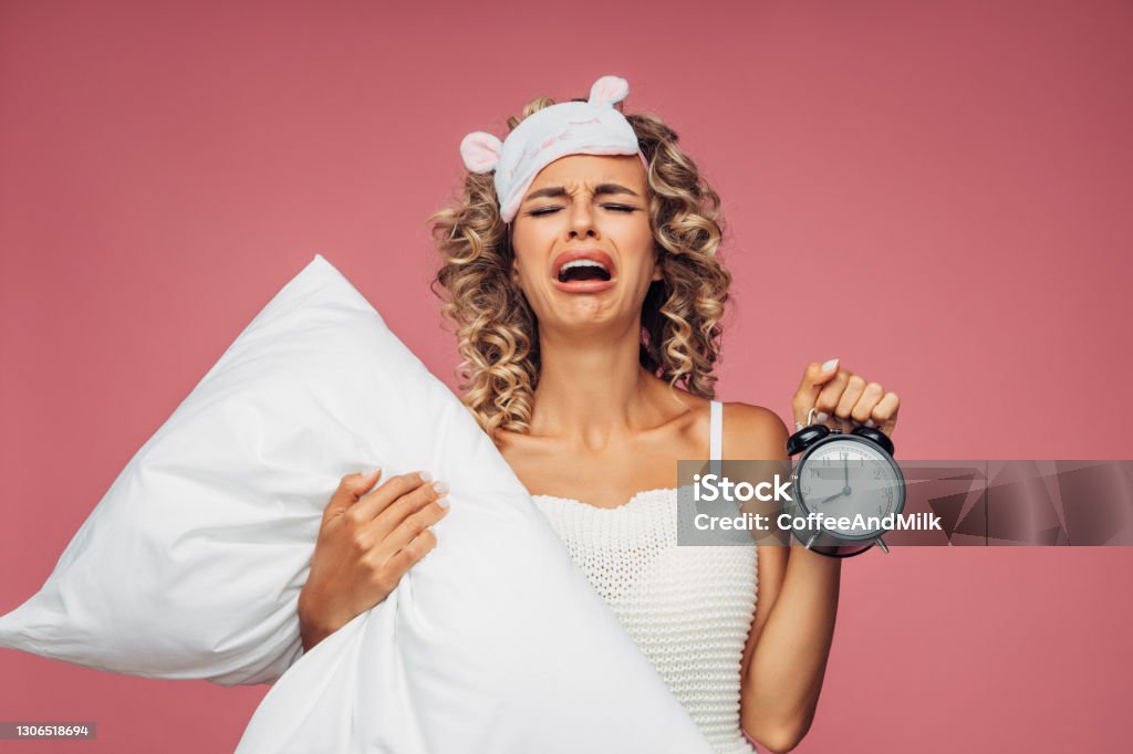 Portrait of a fresh and lovely woman with pillow alarm clock Women Stock Photo