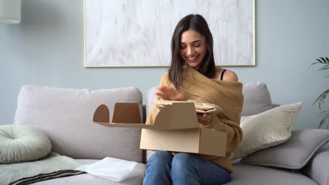 Attractive Indian mixed-race woman customer opening parcel box at home
