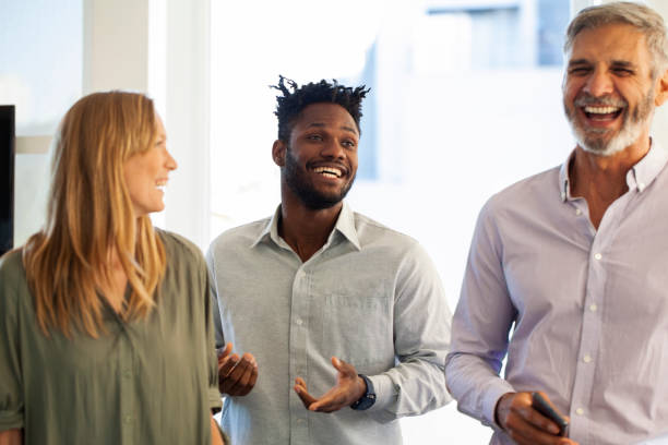 istock Cheerful office colleagues laughing while standing in office 1306518943