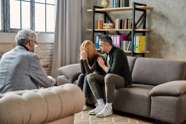 istock Young woman crying beside comforting husband 1306519017