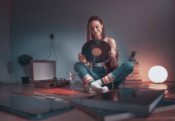 woman listening music on gramophone with vinyl in her hands - old record imagens e fotografias de stock