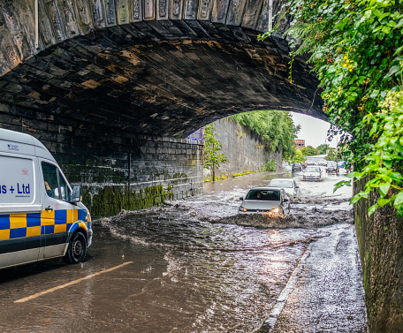 Glasgow, Scotland - Traffic delays as drivers negotiate their way through a deep flood on a street, following heavy rainfall.