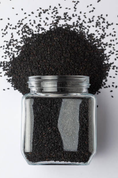 Organic Black Sesame seeds(Sesamum indicum) or Black Til with shell, spilled and in a glass jar. Top view