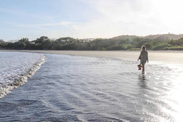 istock Young woman walks down sandy beach in the morning 1306525837