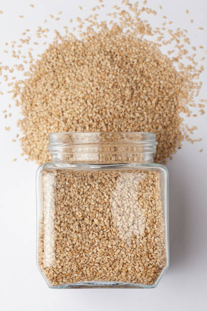 istock Organic White Sesame seeds(Sesamum indicum) or white Til with shell, spilled and in a glass jar. 1306525873