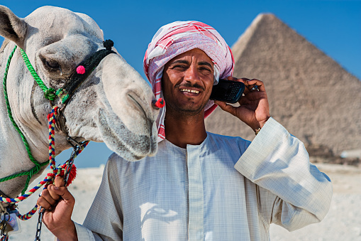 Bedouin on the phone, pyramids on the background, Giza, Egypt.