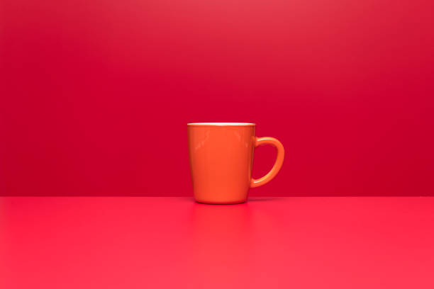 istock orange color coffee or tea cup on red background 1306532164