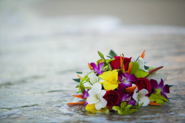 On the shore of Jamaica, after a destination wedding a bride's bouquet is touched by the seawater as a wave comes ashore.