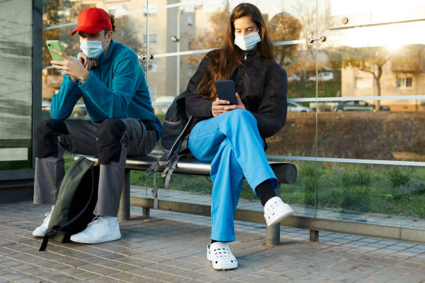 istock Essential workers at the bus stop looking at their phones. 1306533928