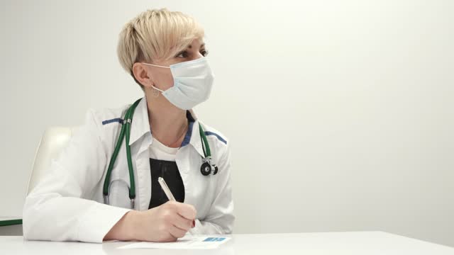 Middle age female doctor in protective mask talking ro patient at clinic