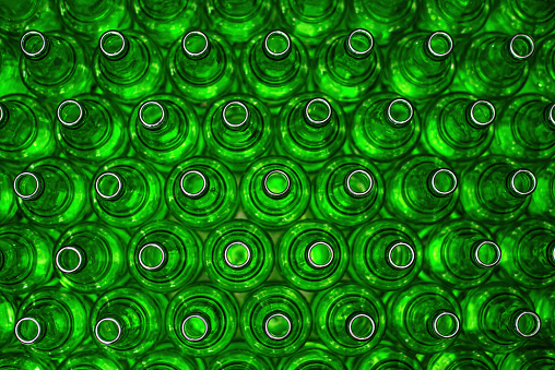 Rows of green glass bottles on the conveyor close-up. Bottle pattern