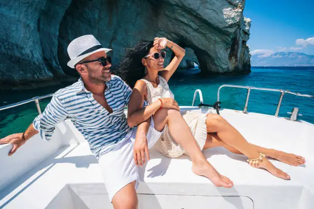 Couple in love enjoying summer vacations on a yacht in Zakynthos Greece - Navagio beach and having fun traveling again during coronavirus outbreak