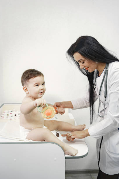 Pediatrician in a white coat examines baby with a stethoscope stock photo