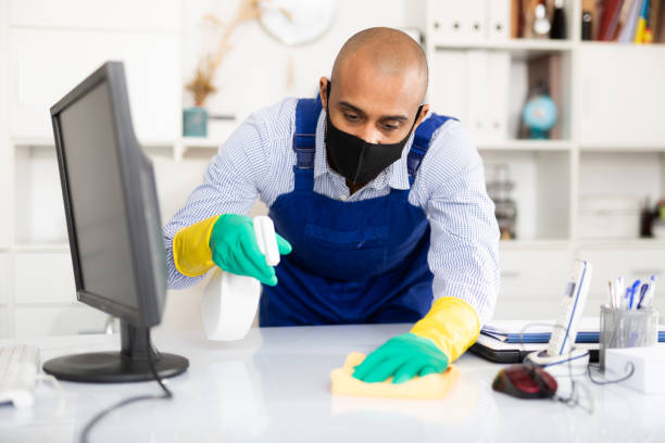 istock Man in protective mask and in an overalls cleans the table 1306540347