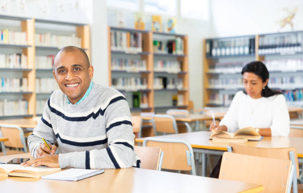 istock Cheerful adult hispanic student studying in university library 1306540792