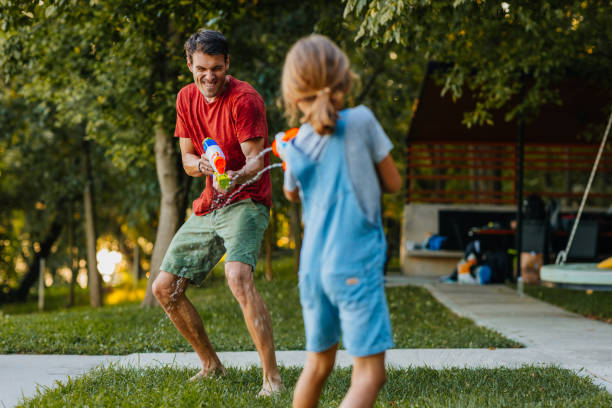 istock Father and daughter playing with squirt guns 1306542650