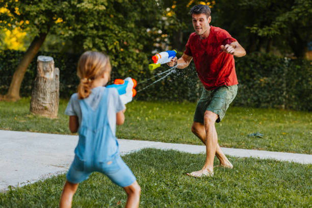 istock Father and daughter splashing with squirt guns 1306542670