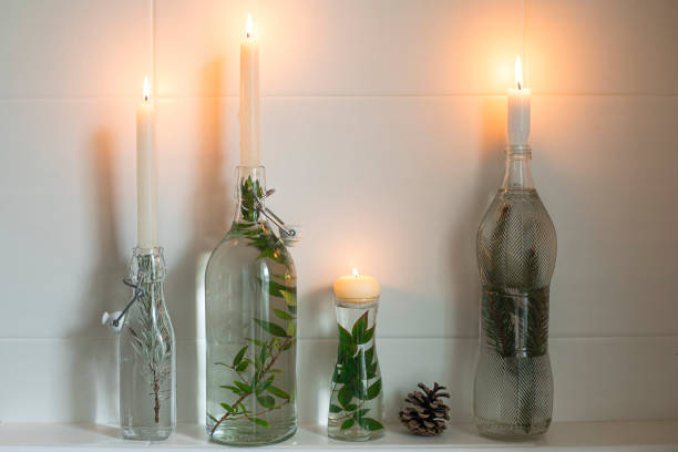 Candles in bottles filled with water and greenery, home decor idea for Christmas. stock photo