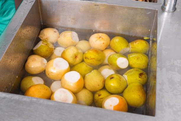 un gruppo di alcune pere gialle in un lavandino mezzo pieno d'acqua. - half full apple green fruit foto e immagini stock