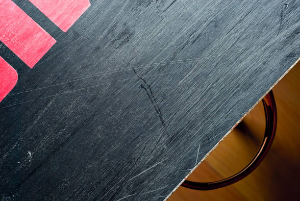 istock White scratches and dust on black plastic. Scratches on a snowboard close up. Paraffin application and ski equipment service. 1306554174