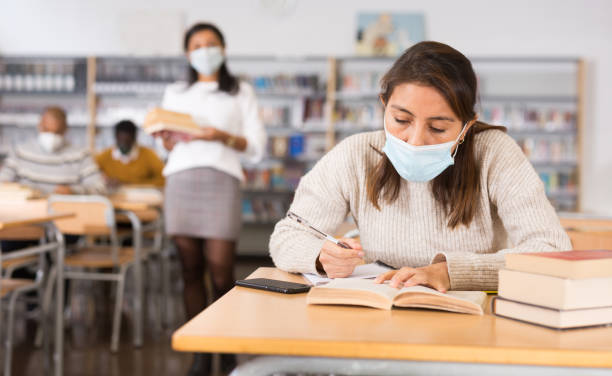 istock Woman wearing mask studying in public library 1306559390