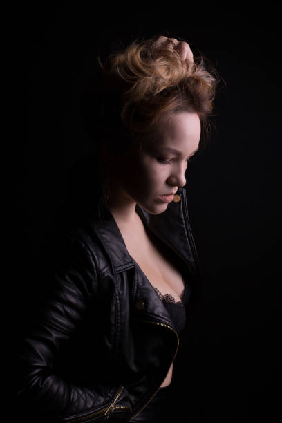 ritratto drammatico di giovane modella con lussureggianti capelli ondulati, indossa giacca di pelle, posando con l'ombra sul viso - 6139 foto e immagini stock