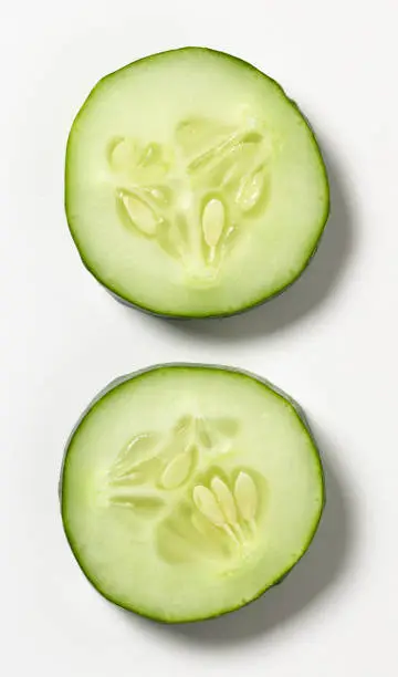 Two slices of cucumber photographed from overhead on a white background.