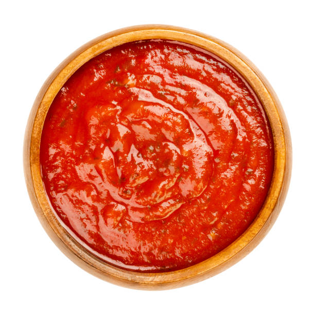 Arrabbiata sauce, spicy Italian tomato sauce in a wooden bowl Arrabbiata sauce in a wooden bowl. Spicy Italian tomato sauce for pasta, made from tomatoes, garlic and dried red chili peppers, cooked in olive oil. Vegan sugo. Close-up over white, macro food photo. savory sauce stock pictures, royalty-free photos & images