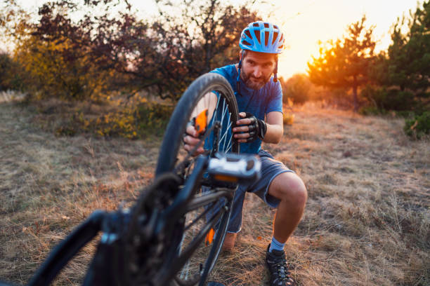 istock Man repairing his biker wheel in nature 1306566708