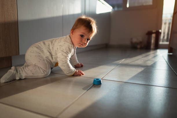 baby boy on the tiled floor looking at the camera - baby tile crawling tiled floor imagens e fotografias de stock
