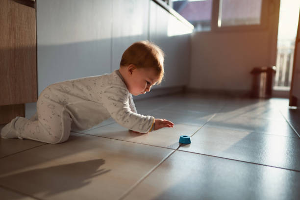 side view of a baby boy grabbing a toy on the floor - baby tile crawling tiled floor imagens e fotografias de stock