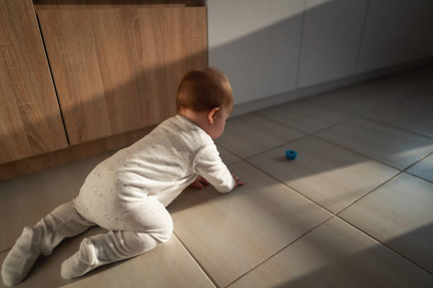 high angle view of a baby boy crawling on the tiled floor - baby tile crawling tiled floor imagens e fotografias de stock