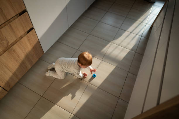 high angle view of a baby boy grabbing a toy on the floor - baby tile crawling tiled floor imagens e fotografias de stock