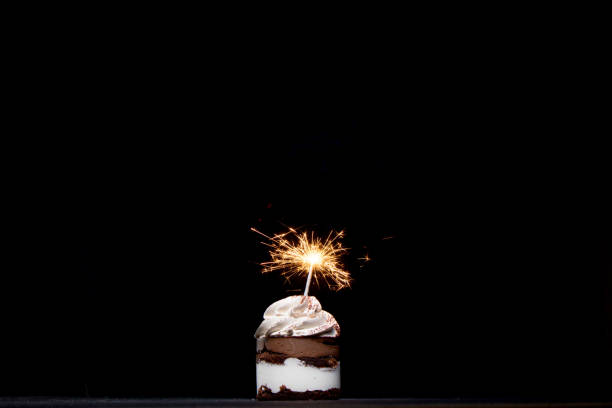 istock Delicious birthday cupcake with firework candle on table against dark background. 1306567848