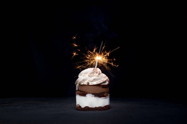 istock Delicious birthday cupcake with sparkler on dark table 1306567854