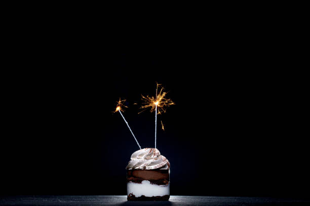 istock Delicious birthday cupcake with sparkler on dark table 1306567870