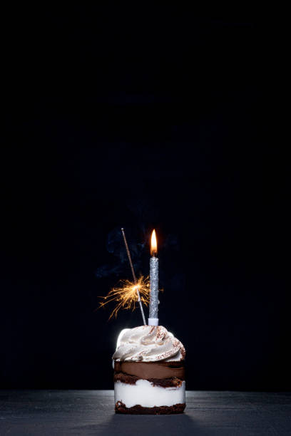 istock Birthday Cake with a candle on a black background 1306567911