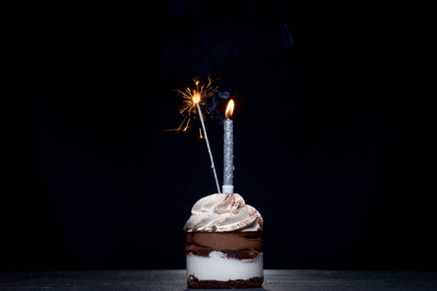 istock Birthday Cake with a candle on a black background 1306567932