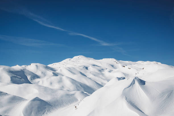 Sunny winter in European Alps, snow capped mountains to where the eye can see. White mountains glistening in the sun. No people, winter mountains in perfect weather conditions.