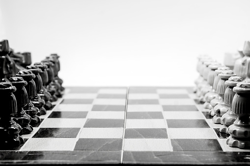 A selective focus shot of chess pieces on a board in grayscale