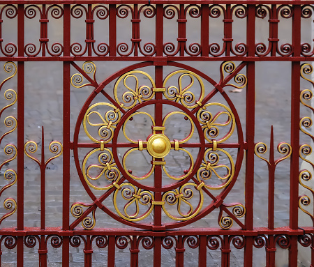 Ornate and beautiful wrought iron fence gate painted scarlet red and gold