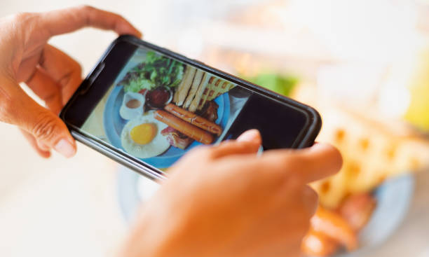 istock Close-up female hand using smartphone taking  breakfast meal  for upload file to online on Internet . 1306573012