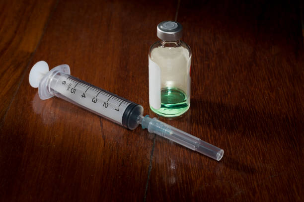 istock Syringe and medicine ampule on wooden table. 1306585008